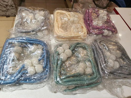 Packaged braided curtain tieback ropes with white beaded ends in grey, cream, purple, blue, green, and silver colors.