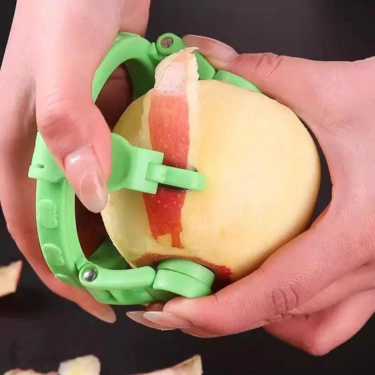 Green handheld rotating apple peeler removing the skin from an apple.