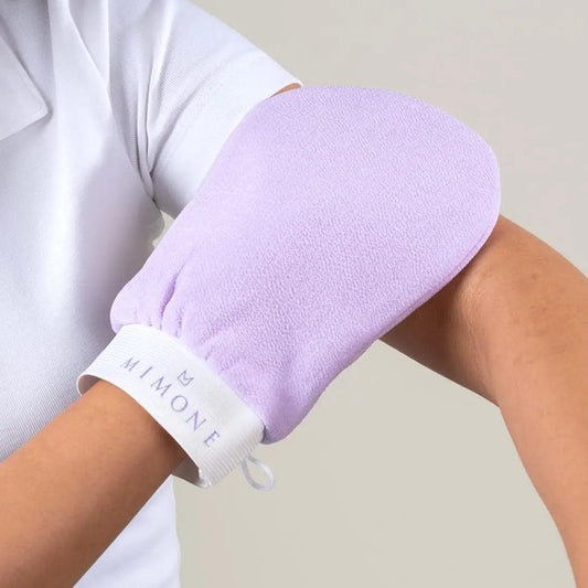 Person wearing a soft purple exfoliating bath glove to scrub their arm during body cleansing.